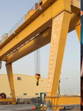 Yellow goliath gantry crane with a lifting hook outside an industrial building