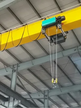 Yellow overhead crane hoist and hook running on a roof-mounted runway beam