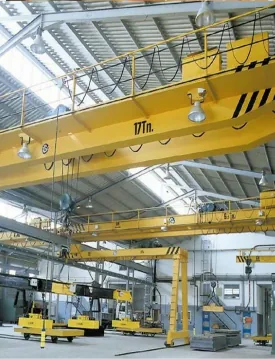 Two yellow overhead travelling cranes spanning a factory production hall
