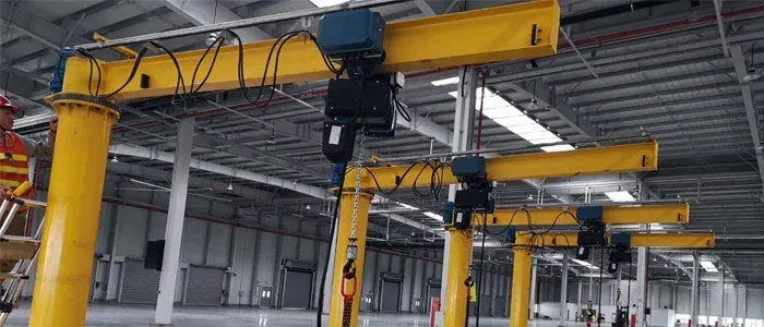 Yellow jib crane installed in an empty industrial warehouse
